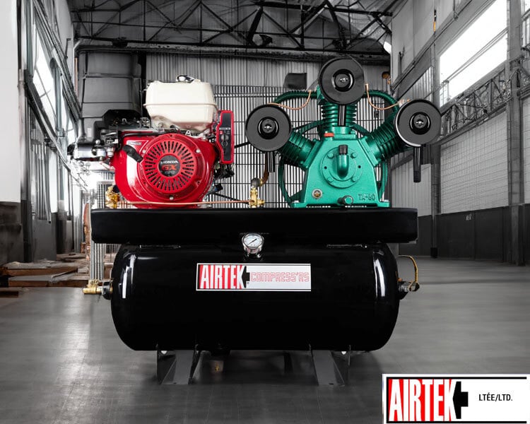 Heavy-duty Airtek industrial air compressor with red and green motors, strategically positioned in a spacious, empty warehouse.