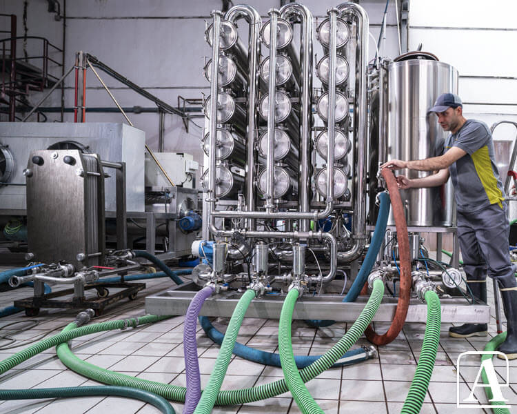 Technicien travaillant sur des machines dans une usine avec des tuyaux Amiflex visibles dans l'espace de travail.