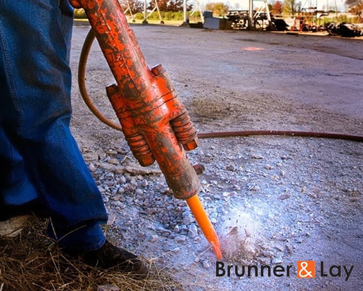 Close-up of a concrete buster tool being used to break up concrete on a construction site