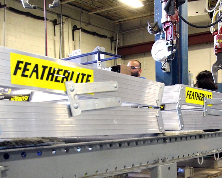 Featherlite aluminum beams on an industrial assembly line, showcasing high-quality industrial ladders.