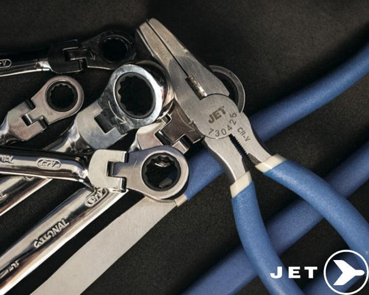 A collection of metal wrenches of varying sizes and shapes arranged on a dark surface, partially overlaying some blue pipes, with a prominent logo of the brand jet in the corner.