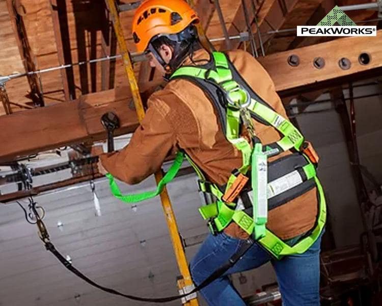 A construction worker wearing a safety helmet and harness is installing overhead equipment. the scene depicts an emphasis on workplace safety in an industrial setting.